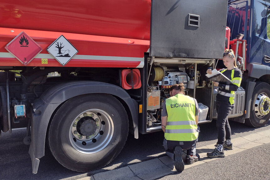 Überprüfung eines Tankwagens: Zwei Bedienstete des Eichamts stehen vor der Messanlage und kontrollieren deren Gesetzeskonformität